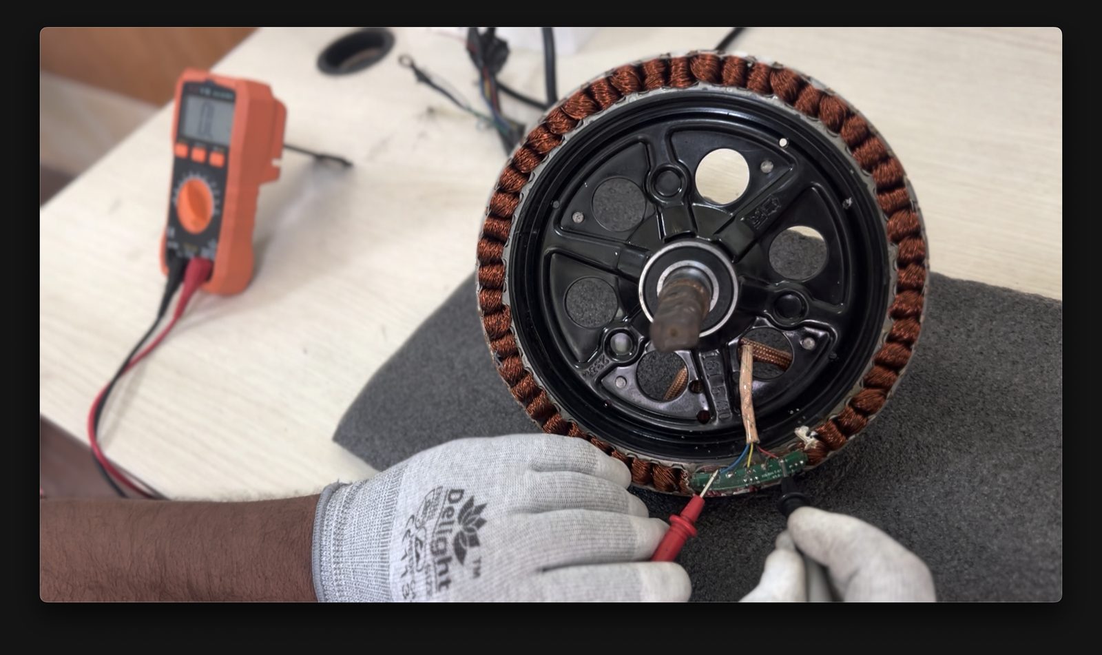 Technician testing a BLDC hub motor stator with a multimeter